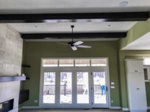 A living room with freshly painted walls, a new ceiling fan, and exposed beams by Grabill Painting and Drywall in Fort Wayne, IN.
