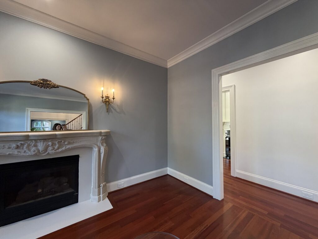 A living room with light blue walls, white trim, and a fireplace, showcasing painting work by Albis Morales Painting LLC in Raleigh, NC.