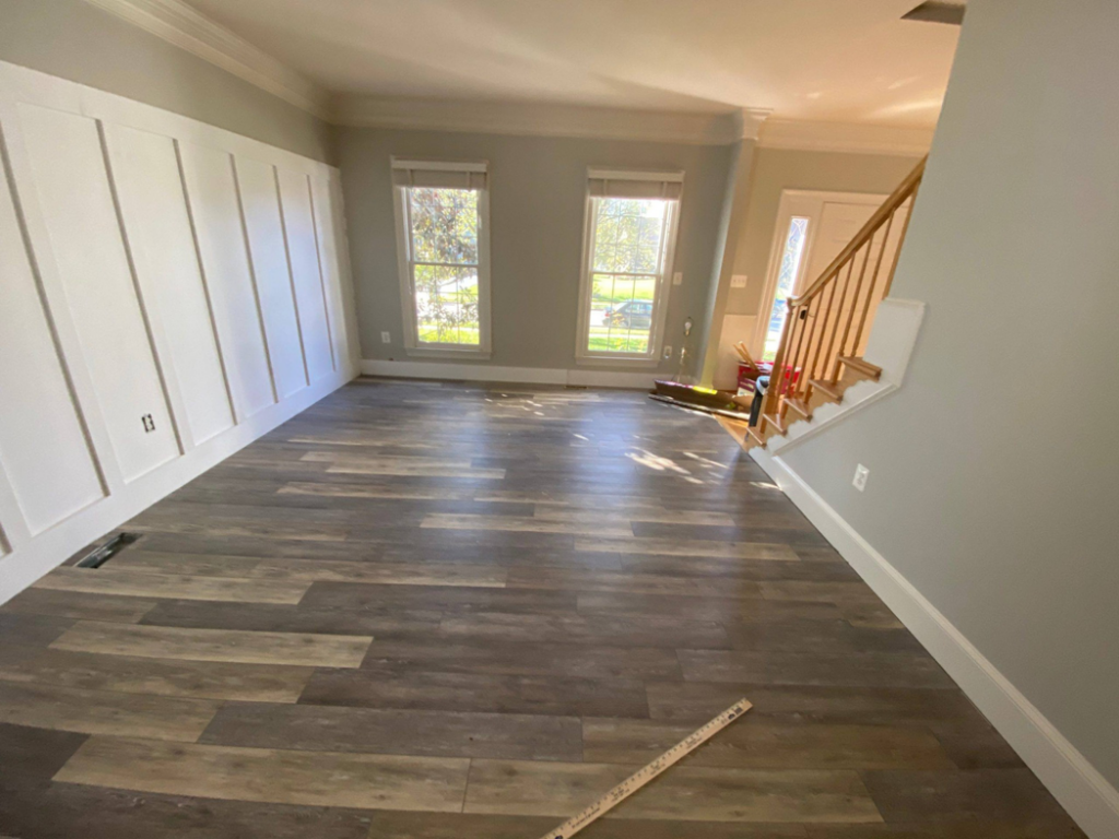 A living room undergoing renovation with new plank flooring and board and batten wall installation by Amazing Handyman in Peoria, IL.