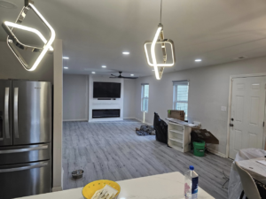 A modern living room with new flooring, light fixtures, and a fireplace, showing a home improvement project by All Trades Home Improvement in Hobart, IN.