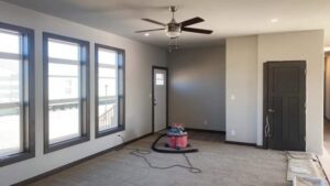 A living room undergoing renovation, showing new paint, windows, and a shop vacuum, by EJ Drywall Plus in Kearney, NE.