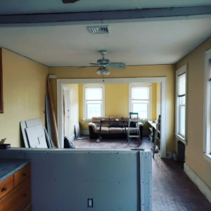 Living room renovation in progress with construction materials and a partially finished wall by CJM Builders Inc in Wilmington, MA.