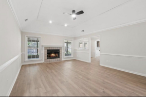 A newly renovated living room with new flooring and a fireplace by All Pro Roofing and Renovations in Sachse, TX.
