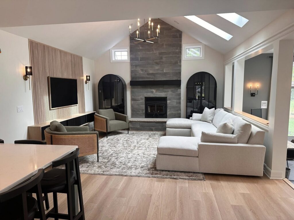 A living room renovation with a stone fireplace, vaulted ceiling, and wood accent wall by Antalek Construction LLC in Erie, PA