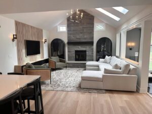A living room renovation with a stone fireplace, vaulted ceiling, and wood accent wall by Antalek Construction LLC in Erie, PA