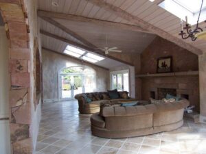 A beautifully renovated living room featuring vaulted ceilings, exposed beams, and a stone fireplace by Rice Building Company in Rocky Mount, NC.