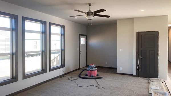 A living room undergoing renovation, featuring new paint, windows, and a shop vacuum, handled by EJ Drywall Plus in Kearney, NE.