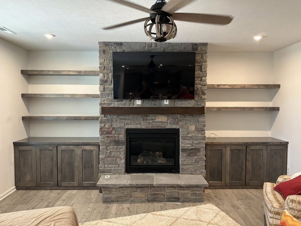 A living room featuring a newly installed stone fireplace with custom built-in shelves by Benjamin Design - Build in Fishers, IN.