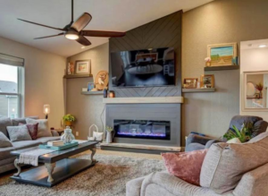 Living room with mounted TV, custom fireplace, and ceiling fan installed by SMB Construction in Toledo, OH.