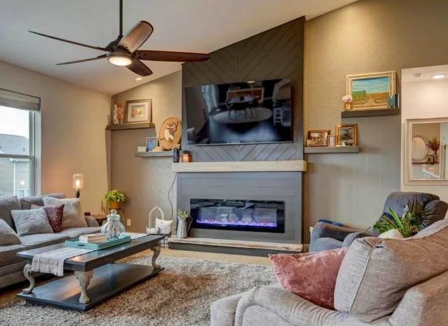 Living room with mounted TV, custom fireplace, and ceiling fan installed by SMB Construction in Toledo, OH.