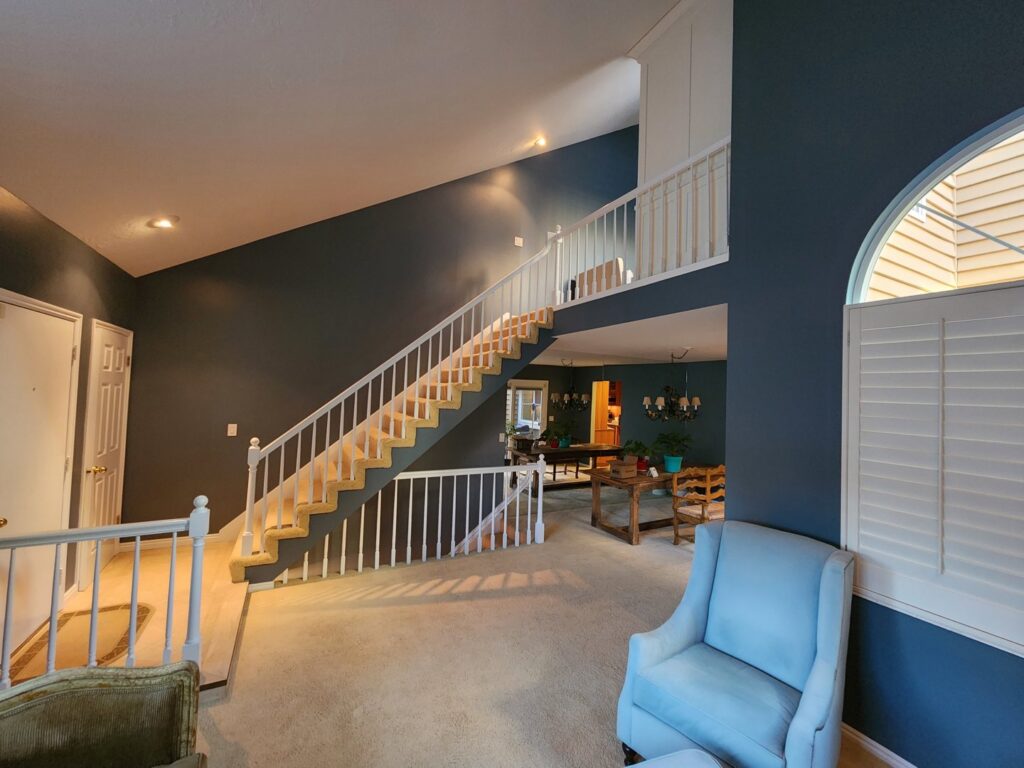 A spacious living room with dark blue walls and a renovated white staircase, completed by Branham Handyman in Salt Lake City, UT