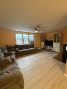 A living room featuring newly installed light laminate flooring and a large sectional sofa by MPH Design in Philadelphia, PA.