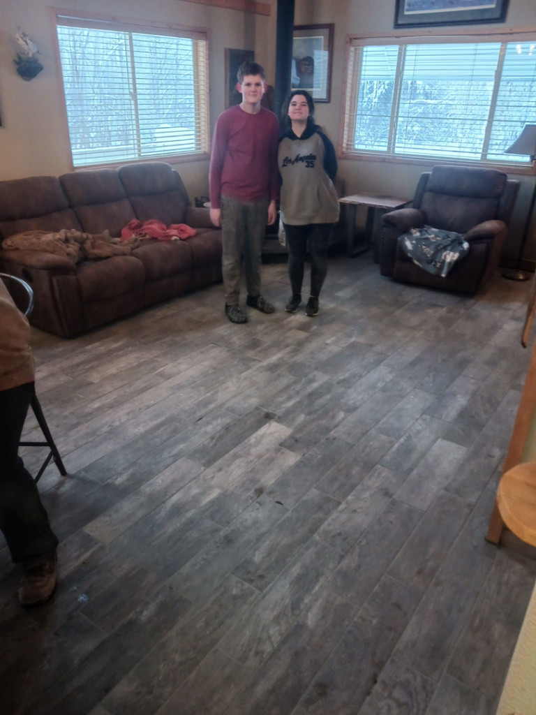 A living room with newly installed wood-look tile flooring, a project by RS handyman llc in Kenai, AK.