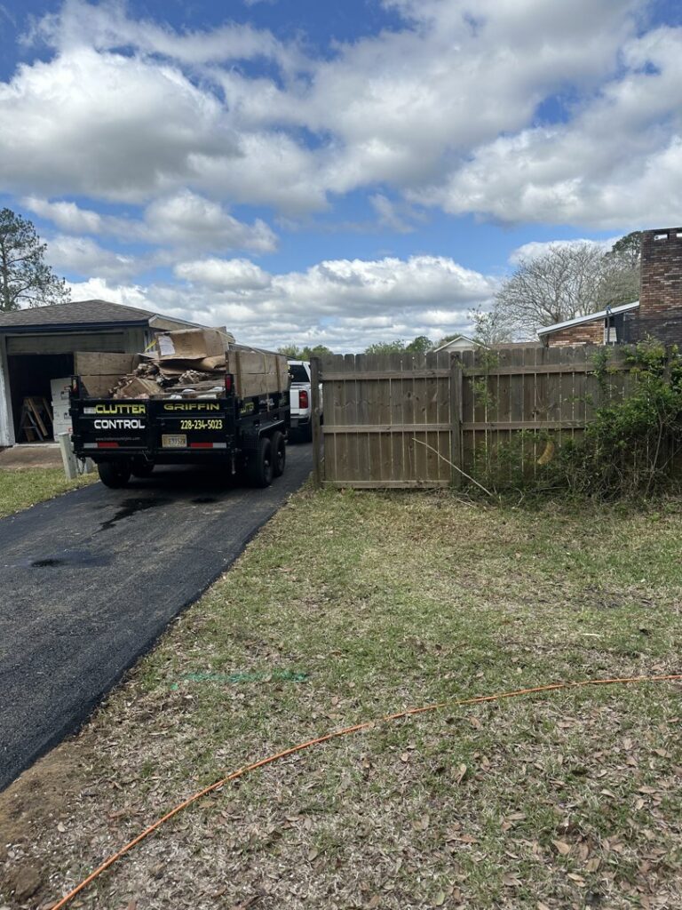 A Clutter Control Junk Removal and Demo dump trailer loaded with cardboard boxes and debris, ready for transport in Biloxi, MS.