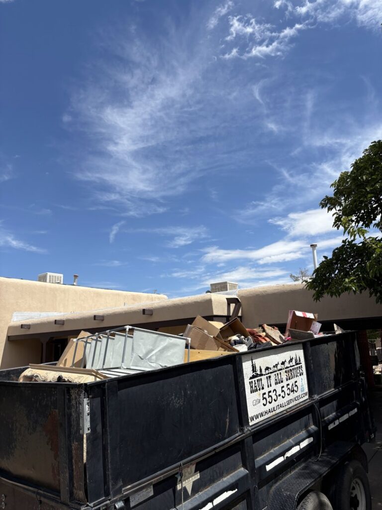 A loaded Haul It All Services junk removal trailer parked at a residential house in Albuquerque, NM