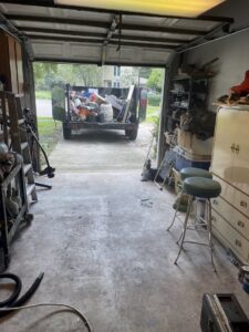 A loaded junk removal trailer visible through an open garage door, indicating a completed job by Junk Removal JAX in Jacksonville, FL.