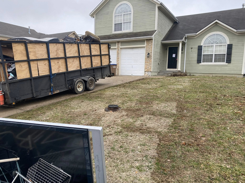 A Harris Family Hauling & Snow Removal LLC trailer fully loaded with junk in a residential driveway in Independence, MO.
