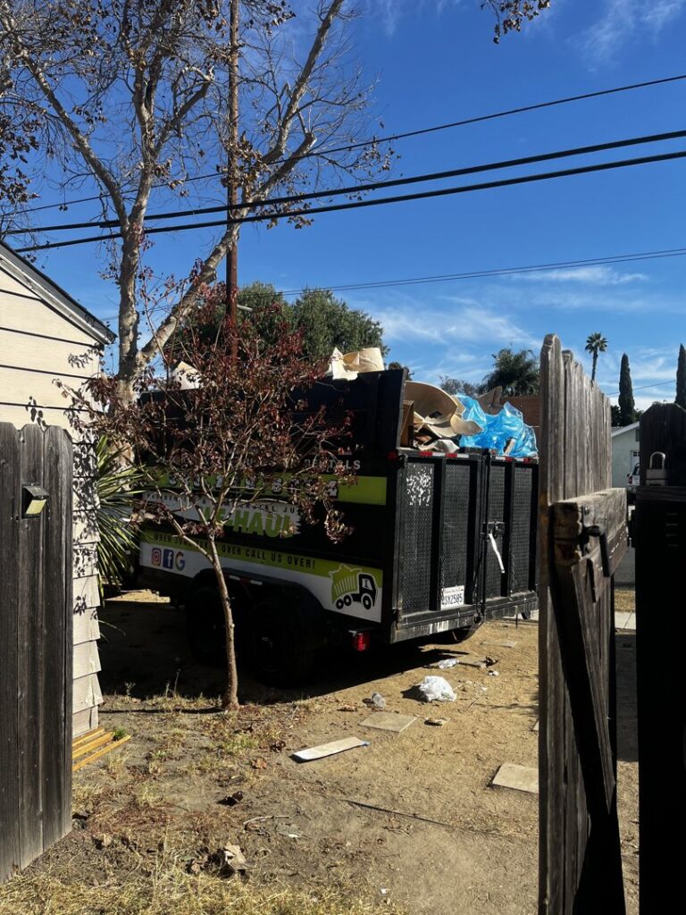 A We-Haul Junk Removal trailer fully loaded with various items, parked in a residential area after a junk removal job in Long Beach, CA