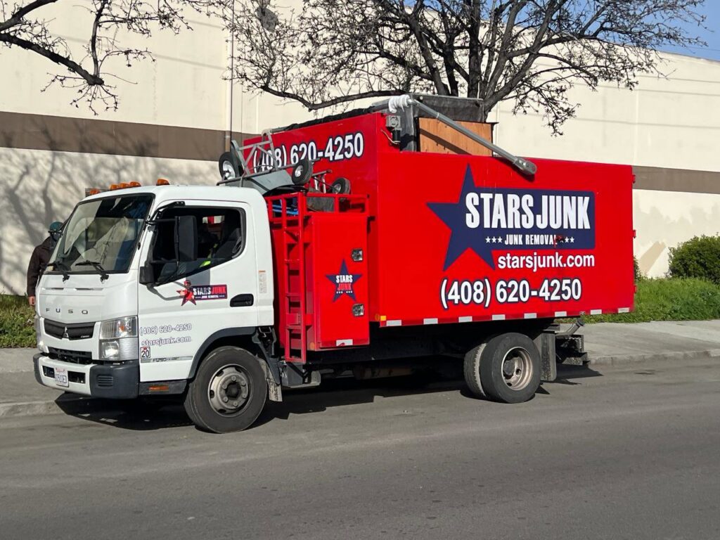 A red Stars Junk Removal truck loaded with various items of junk, parked on a street in San Jose, CA.