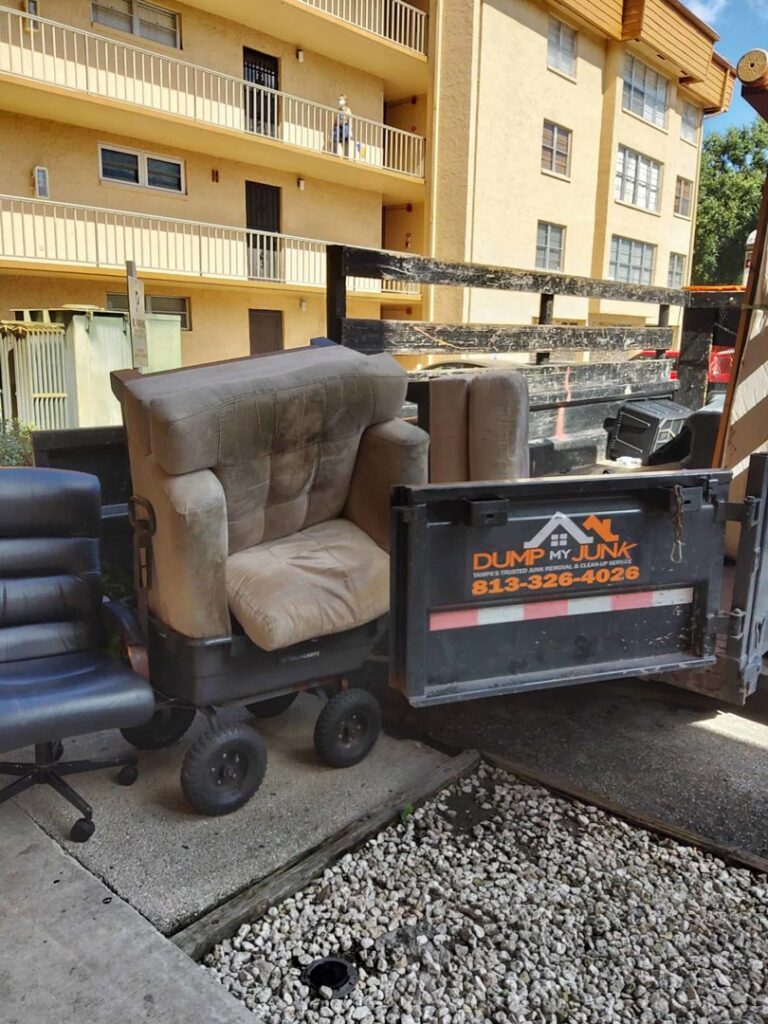 An armchair being loaded onto a junk removal truck by Dump My Junk LLC Demolition & Dumpster Rental in Tampa, FL.