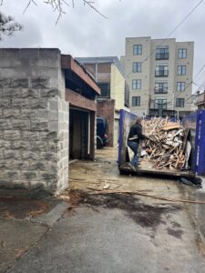 A worker loading wood debris from a renovation project into a Toss-It dumpster in Glen Burnie, MD.