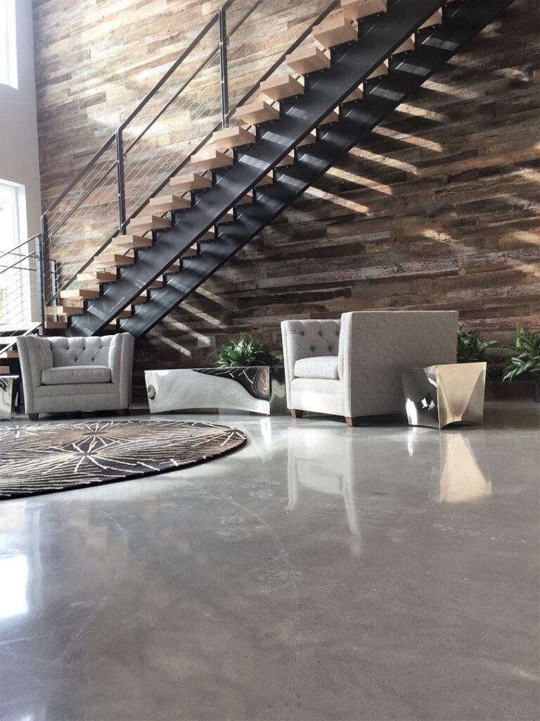 A lobby area with polished concrete floors, wooden stairs, and seating by Heavy Duty Floors, LLC in New Britain, CT.