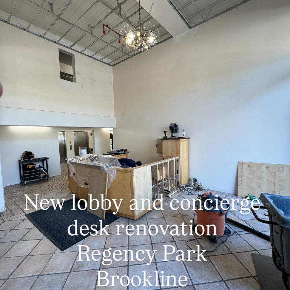 A lobby renovation in progress with exposed ceiling and partially built desk by Markos Construction in Cambridge, MA.