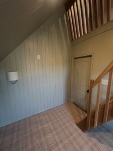 Interior view of a remodeled loft featuring vertical wall paneling and a modern wall sconce by H4 Construction and Remodeling in Blue Springs, MO.