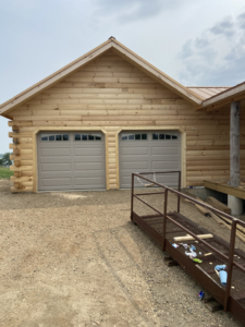 Exterior view of a log cabin style house with new garage doors and a construction ramp, completed by RT Handyman LLC in Sioux Falls, SD.