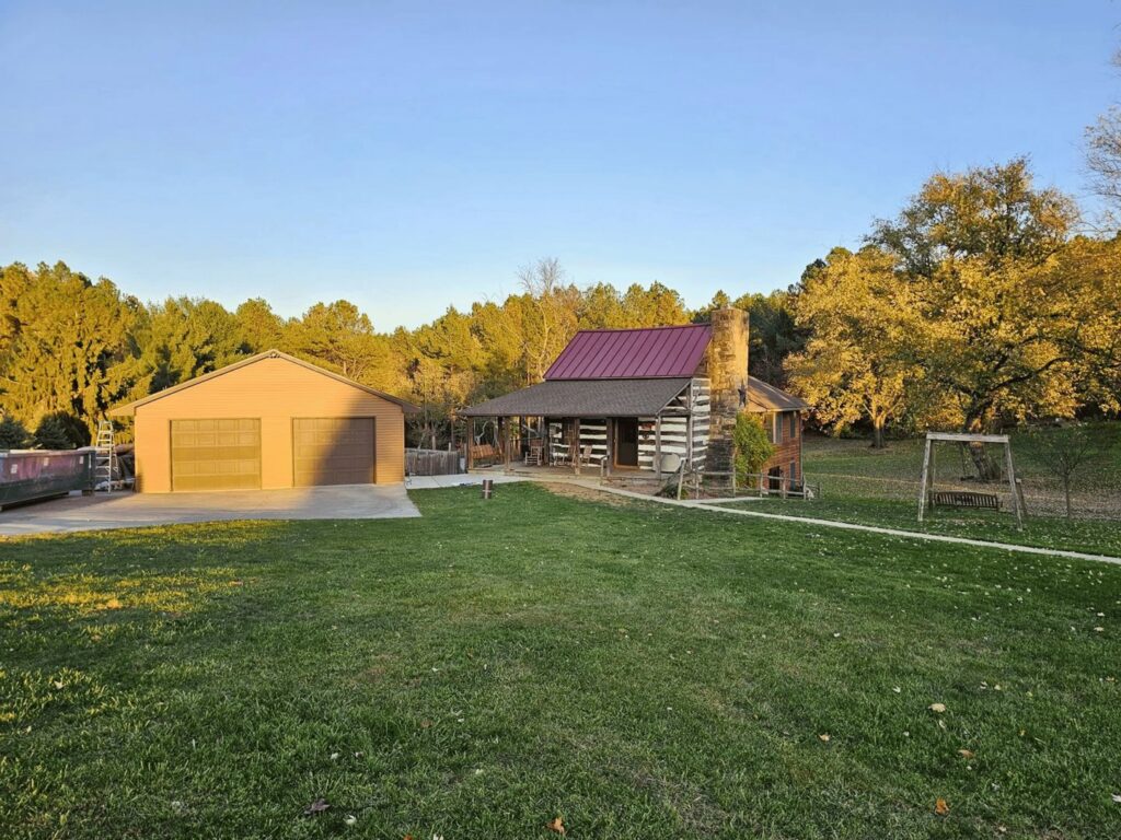 A log cabin style house with a new red metal roof and brown shingle roof installed by Moonshot Roofing in Columbia, PA.