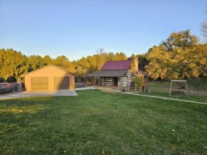 A log cabin style house with a new red metal roof and brown shingle roof installed by Moonshot Roofing in Columbia, PA.