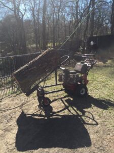 A specialized log lifter moving a heavy tree log, demonstrating efficient cleanup by Anderton Tree Service in Fort Worth, TX
