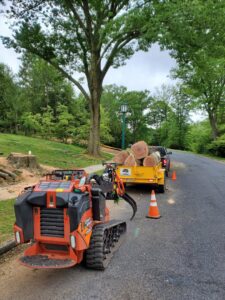 A mini-skid steer and trailer full of logs on a residential street after tree removal by Morgan Brothers Tree Care Solutions in Birdsboro, PA