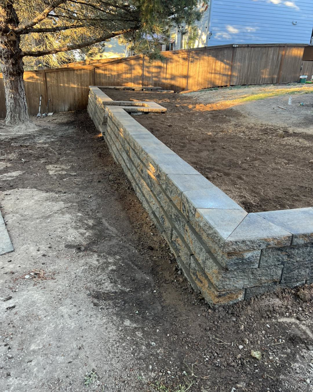 A long, newly installed retaining wall in a backyard, built by MRLM Construction LLC in Beaverton, OR.