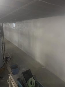 Long basement wall freshly painted white by Calnan Site Development LLC, providing handyman services in Lynn, MA.