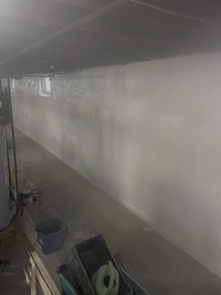 Long basement wall freshly painted white by Calnan Site Development LLC, providing handyman services in Lynn, MA.