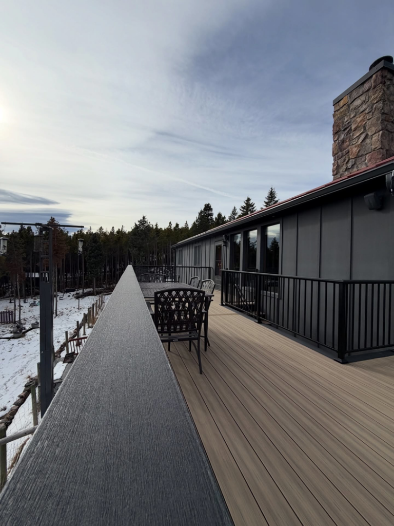 A long perspective view along the sleek black railing of a composite deck, highlighting its length, by AG - Deck Masters in Arvada, CO.
