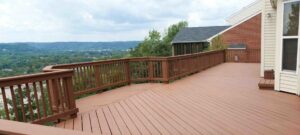 A long wooden deck with railings offering a scenic valley view by St. Charles Deck in St. Charles, MO