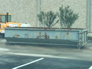 A long, empty gray roll-off dumpster, available for general junk removal projects from Waste Master Dumpster Rental Orlando, FL.