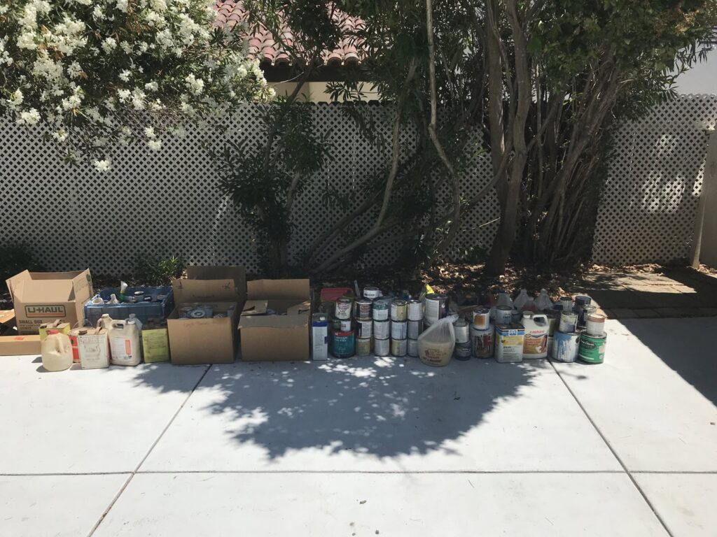 A long line of paint cans and various hazardous waste items arranged for pickup by Hazawaytoday.com in El Segundo, CA