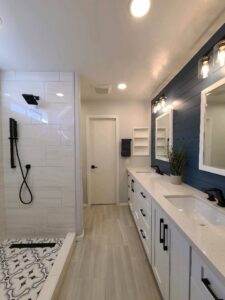 A long, modern bathroom renovation featuring a walk-in shower and double vanity by Integrity Contracting in Cleveland, OH