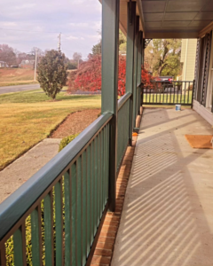 A long view of a freshly painted green porch railing, showcasing completed work by DEMIA 17 & Company LLC in Waldorf, MD.