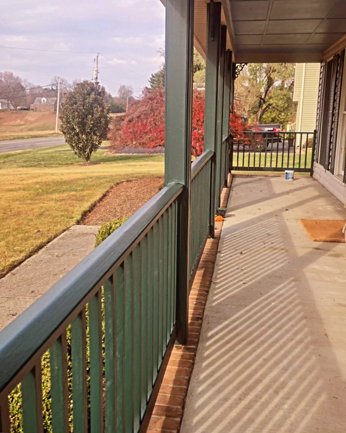 A long view of a freshly painted green porch railing, showcasing completed work by DEMIA 17 & Company LLC in Waldorf, MD.