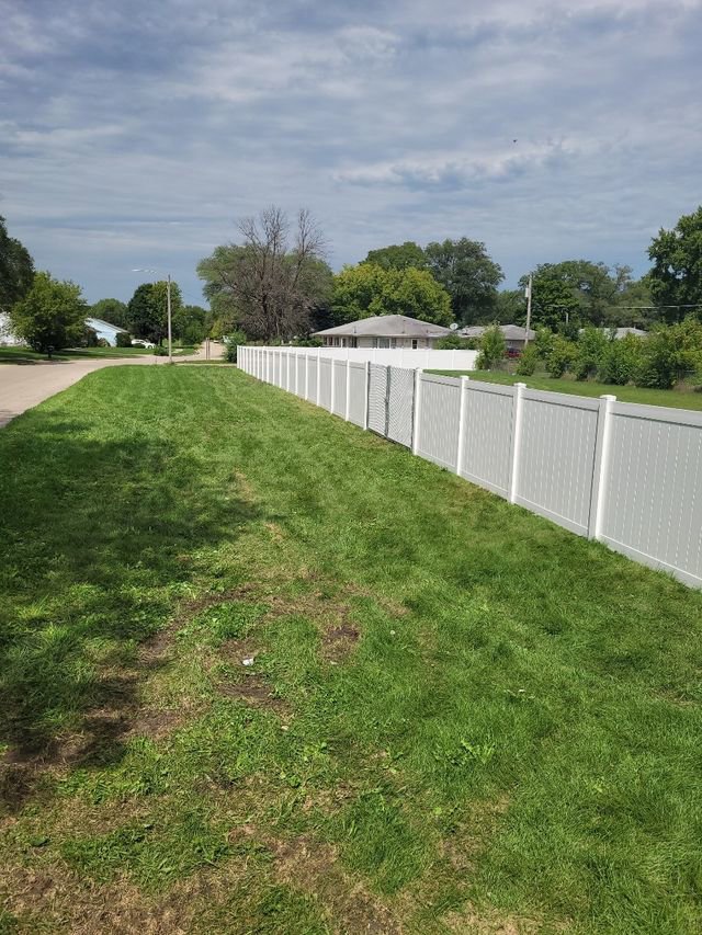 A long white vinyl fence installed along a grassy area next to a road by Badger Vinyl Products in Madison, WI.