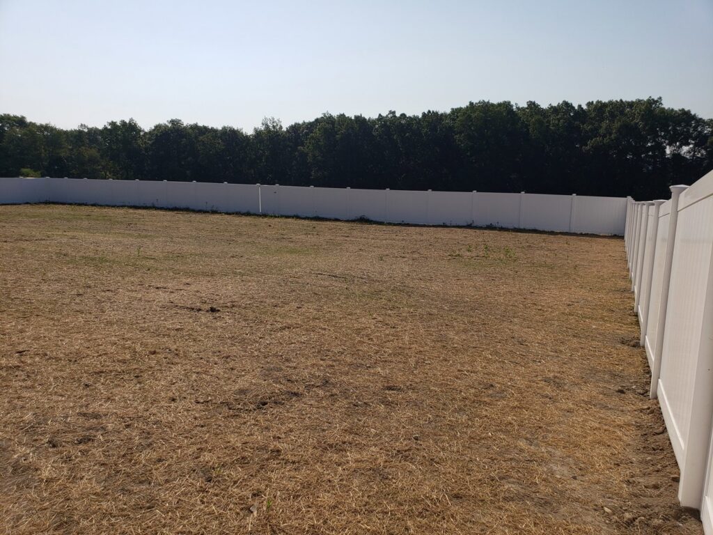 A long white vinyl fence expertly installed around a large field by Lee Fence and Outdoor in York, PA.