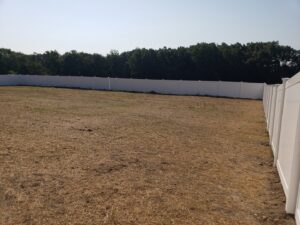 A long white vinyl fence expertly installed around a large field by Lee Fence and Outdoor in York, PA.