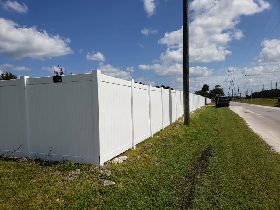 A long white vinyl privacy fence installed along a roadside by Keeler Fence in New Port Richey, FL.