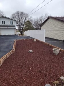 A long white vinyl privacy fence installed along a driveway and garden bed by Badger Vinyl Products in Madison, WI.