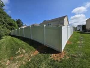 A long, newly installed white vinyl privacy fence in a residential backyard by S&L Decking and Fencing in Charlotte, NC.