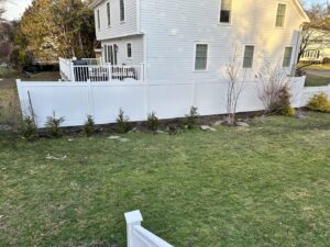 A long white vinyl privacy fence installed along a residential property line by Fence Factory Inc in Stamford, CT
